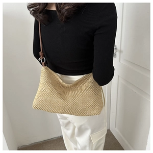 Detailed view of woven straw mesh texture and dark brown knotted leather shoulder strap
