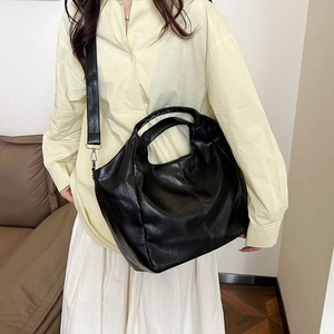 Detail of black leather tote bag showing soft texture and adjustable wide shoulder strap