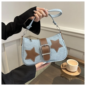 Detail of denim baguette bag featuring brown leather stars and metallic chain accents