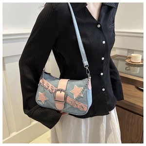 Detail of light blue denim star bag with pink leather accents and silver chain