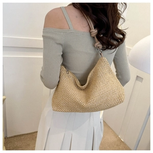 Detail of woven straw shoulder bag featuring textured fabric and knotted strap design