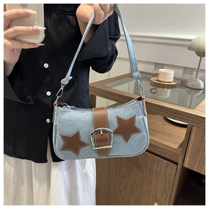 Close-up of denim shoulder bag with brown leather stars and silver metal buckle detail
