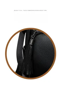 Detail of black pebbled leather texture and metal tassel pendant on travel backpack