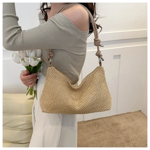 Detail of hand-woven straw shoulder bag with leather strap and knot accent in beige color