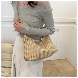 Detail of hand-woven straw crossbody bag featuring semi-moon shape and zipper closure