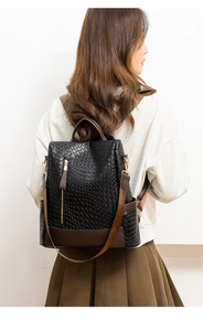 Rear view of black woven PU leather backpack with brown contrast straps on a female model