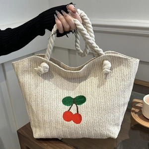 Sac fourre-tout en paille avec broderie cerise et anses en corde blanche par un modèle