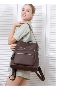 Detail of dark brown leather backpack with multiple zip pockets and adjustable straps