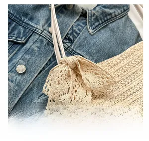 Close-up of straw woven tote bag featuring a large lace bow on blue denim jacket