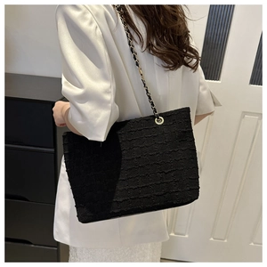 Detail of black tweed tote bag with metal chain strap and golden grommets