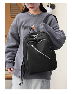Asian model wearing a lightweight black nylon backpack in a modern minimalist interior