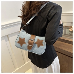 Detail of light blue denim underarm bag with brown leather star and silver buckle