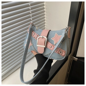 Detail of blue denim and pink leather patchwork bag with star patch and metal buckle