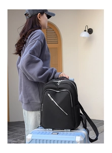Detail of black nylon travel backpack with multi-zipper pockets mounted on luggage