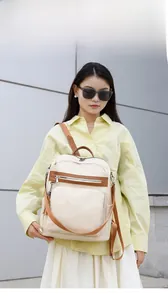 Outdoor shot of beige canvas travel backpack with brown straps worn by a model