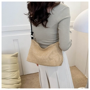 Detail of hand-woven straw hobo bag with black slim shoulder strap on a model