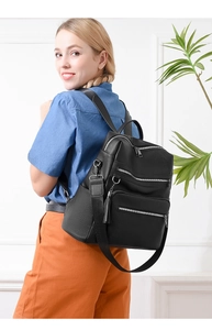 Close-up of black leather backpack with tassel detail and silver zipper compartments