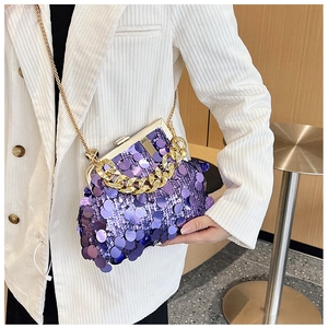 Detail of purple sequin handbag with gold chain strap and metal clasp on white blazer