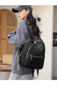 Detail of a black nylon backpack featuring multi-zipper compartments for casual travel