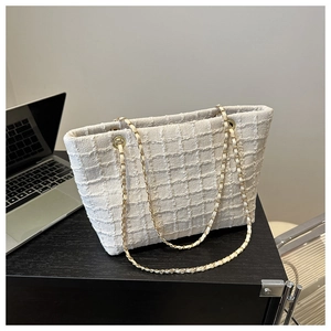 Detail of cream tweed tote bag with classic woven texture and leather chain strap