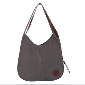 Dark gray canvas shoulder bag with brown leather straps and square brand patch