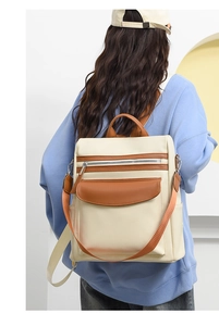 Detailed back view of a cream and brown leather convertible backpack worn by a model