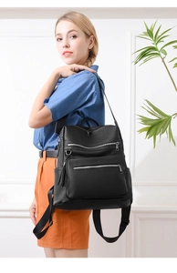 Close-up of black litchi grain leather backpack featuring tassel charms and multiple zippers