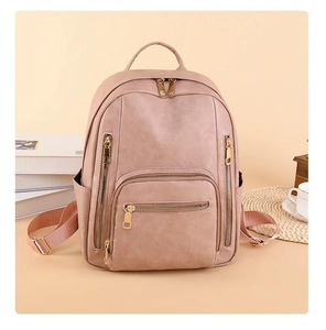 Detail of pink faux leather backpack with gold zippers and multi-pocket design