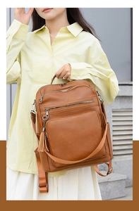 Close-up of brown PU leather backpack with tassel detail and adjustable straps on model