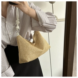 Detail of hand-woven beige straw tote with white rope knot strap and secure zipper