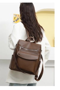 Rear view of a model wearing the dark brown lychee leather convertible backpack on a white wall