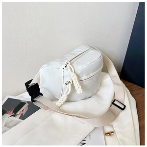 Detail of white nylon crossbody bag featuring woven rope zippers and wide canvas strap