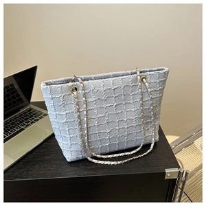 Detail of light blue tweed tote bag with gold chain strap in an office setting