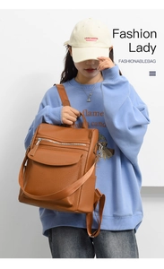 Brown litchi grain faux leather backpack with silver zippers on blue sweatshirt model