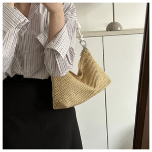 Close-up of woven straw shoulder bag with white leather knotted strap and metal zipper