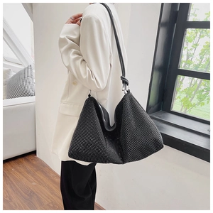 Détail d'un grand sac hobo noir orné de strass brillants avec une bandoulière en cuir