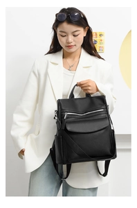 Close-up of a black lychee leather backpack showing detailed front pockets and silver zippers