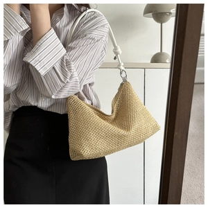 Detail of straw woven underarm bag with white leather strap and knot on a model