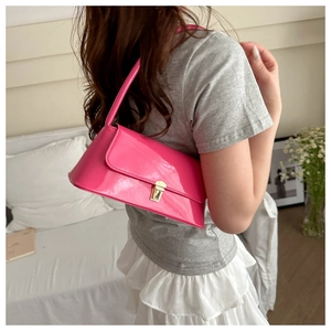 Detail of pink glossy patent leather baguette bag with a gold rectangular metal clasp