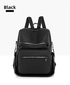 Detail of black backpack showing litchi grain texture, multi-zipper pockets and tassel