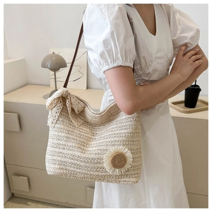 Detail of straw tote bag featuring white lace bow and sunflower floral ornament
