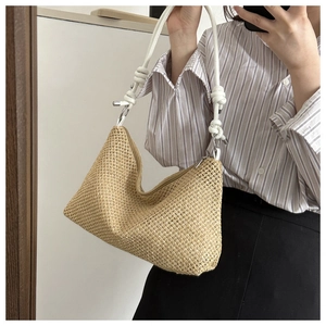 Detail of straw woven tote bag featuring white rope strap and minimalist knots