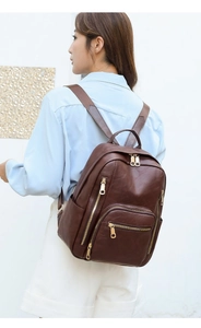 Side view of woman wearing dark brown litchi leather backpack with gold zippers