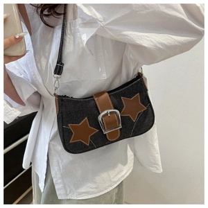 Detailed texture of navy denim underarm bag featuring brown leather stars and silver buckle