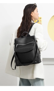 Detail view of a black pebbled leather backpack with multiple pockets on a female model