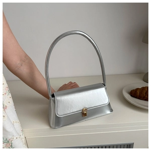 Detailed side view of silver metallic bag featuring a golden buckle and slim shoulder strap