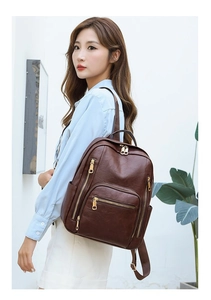 Detail of dark brown leather backpack with gold zippers shown on model in clean setting