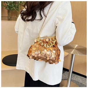 Close-up of golden sequin handbag with metal clasp and decorative chunky chain strap