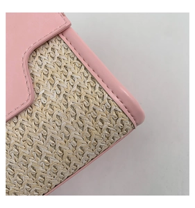Detail von rosa Lederbesatz und natürlicher Strohstruktur an der Handtaschenklappe