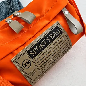 Detailed close-up of orange oxford fabric crossbody bag with vintage sports patch and rivets